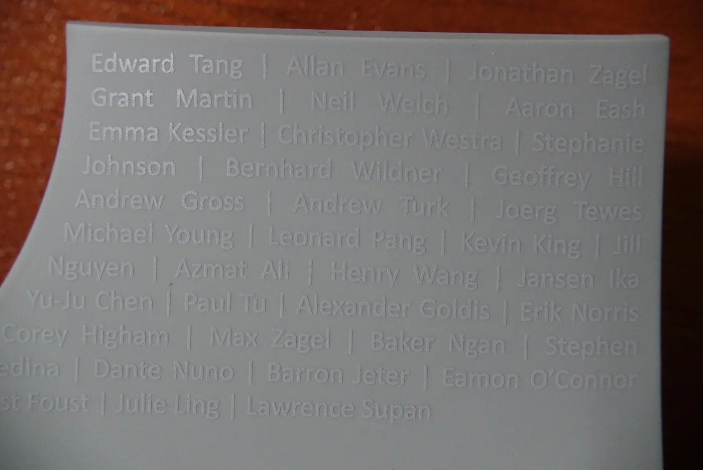 A curved gray part carrying rows of team members' names, including Erik Norris.